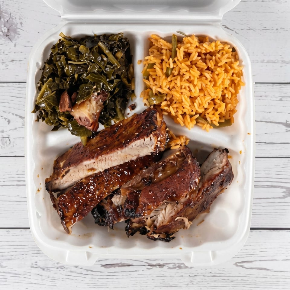 Barbecue ribs with collard greens and seasoned rice in a white takeout container.