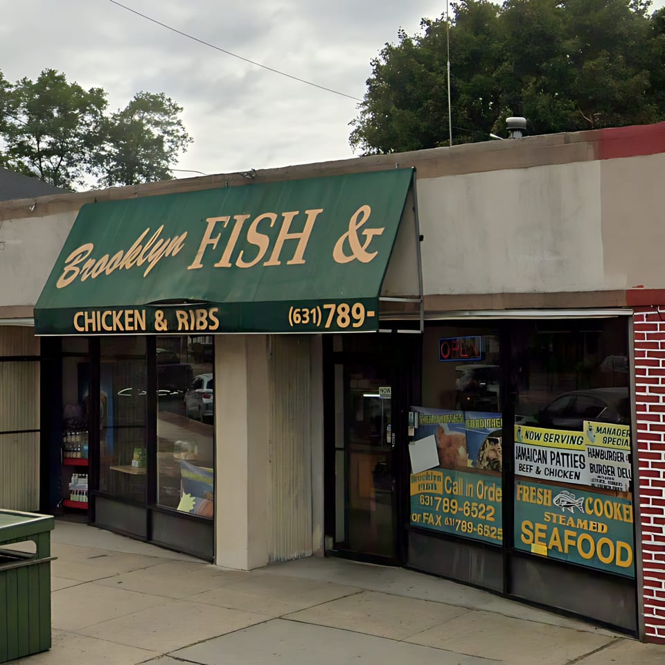 The exterior of Brooklyn Fish & Chicken & Ribs restaurant with a green awning and window signs.